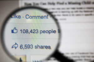 magnifying glass showing closer view of Facebook likes and shares