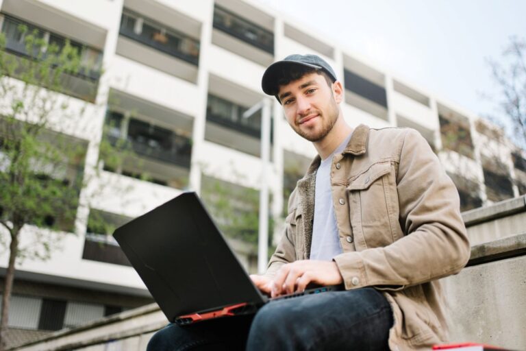 Man typing on laptop outside